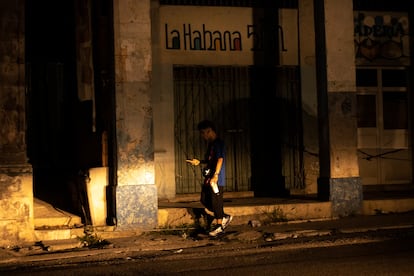 Un joven camina por las calles de Centro Habana alumbrándose con su teléfono móvil. 