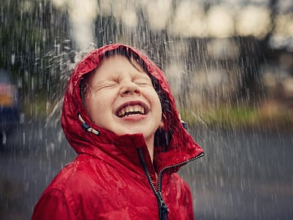 Un niño disfruta con entusiasmo de la lluvia.