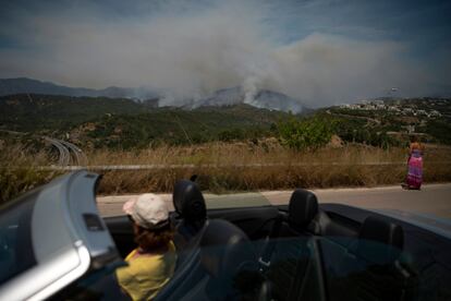 La gente se detiene en la carretera en Benahavís para observar el humo del incendio forestal en la cordillera malagueña.