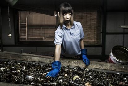 Kaori Kimchi, de 48 años, quita los restos que hay entre las botellas de cristal que serán después reutilizadas en Tokio (Japón).