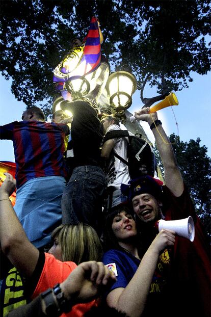 Los aficionados encaramados al monumento que da nombre a ese tramo de Las Ramblas. La tradición cuenta que aquel que beba volverá a la Ciudad Condal.