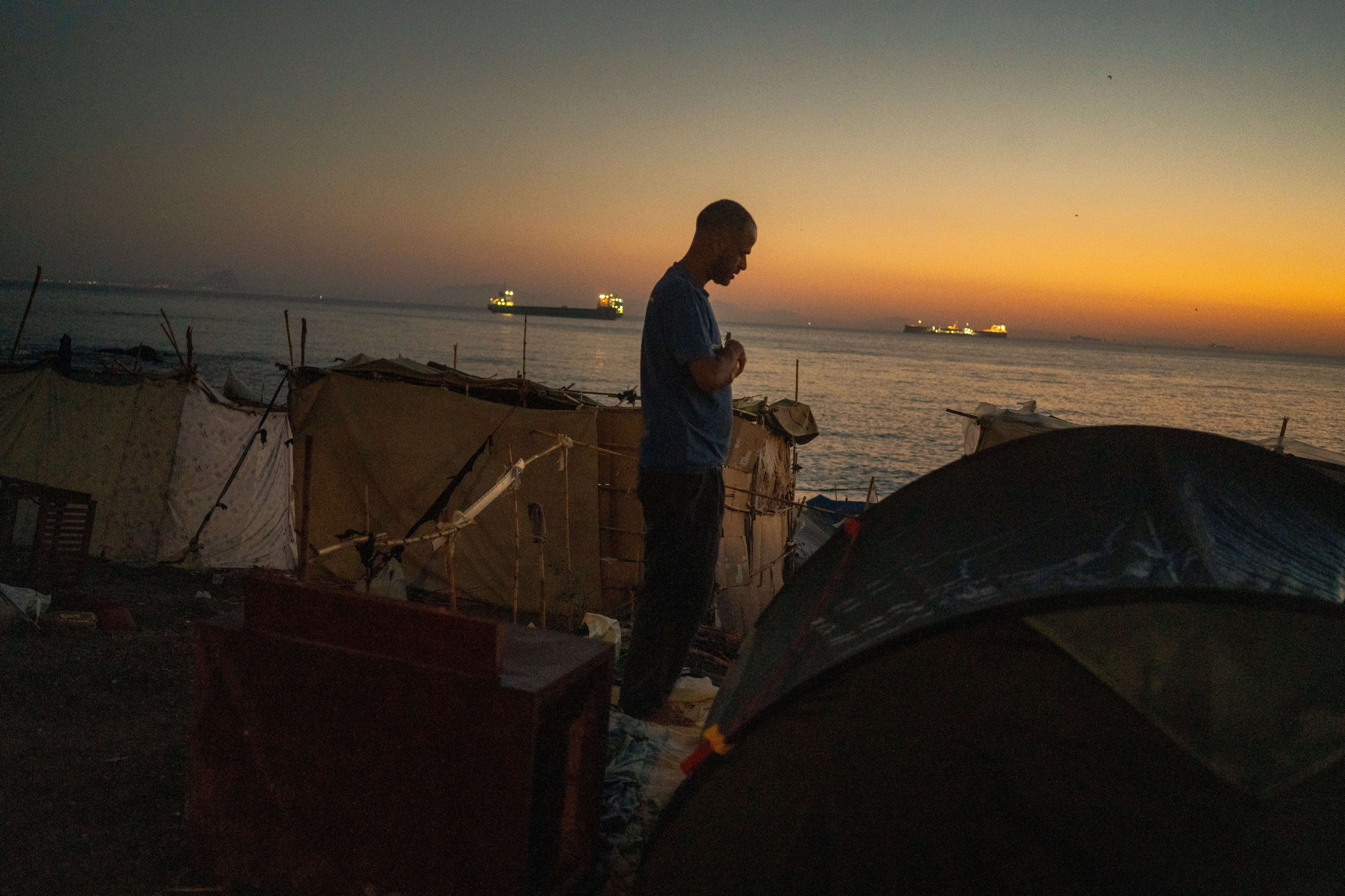 Un hombre reza al amanecer en la playa del Trampolín.