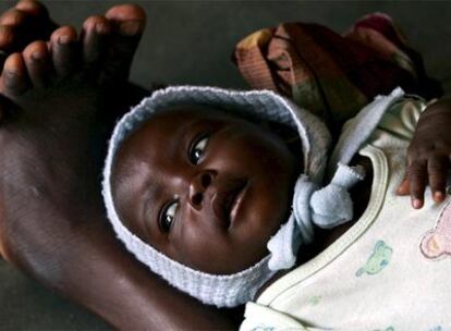 Un pequeño espera tumbado sobre las piernas de su madre para recibir atención médica en el centro de investigación sobre la malaria de Manhiça (Mozambique).