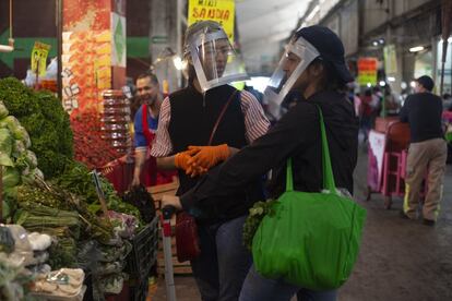 Una familia visita la central de abastos para comprar alimentos con mascarillas improvisadas.