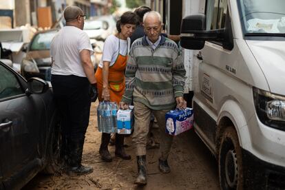 Un vecino de Algemesí (Valencia) recoge agua y leche de un camión con ayuda humanitaria el 6 de noviembre.