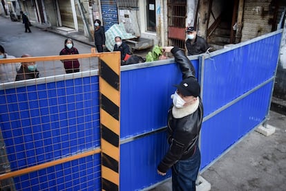 Un hombre entrega comida a un persona en un barrio aislado de la ciudad china de Wuhan, el 23 de febrero. 