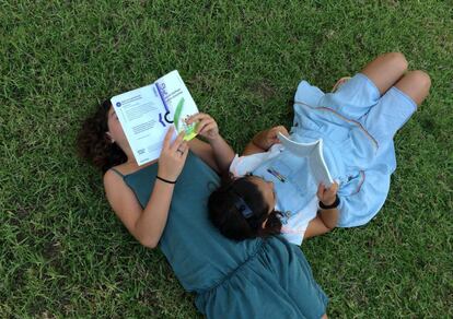 Dos niñas leyendo, o simulando que leen, en un parque.