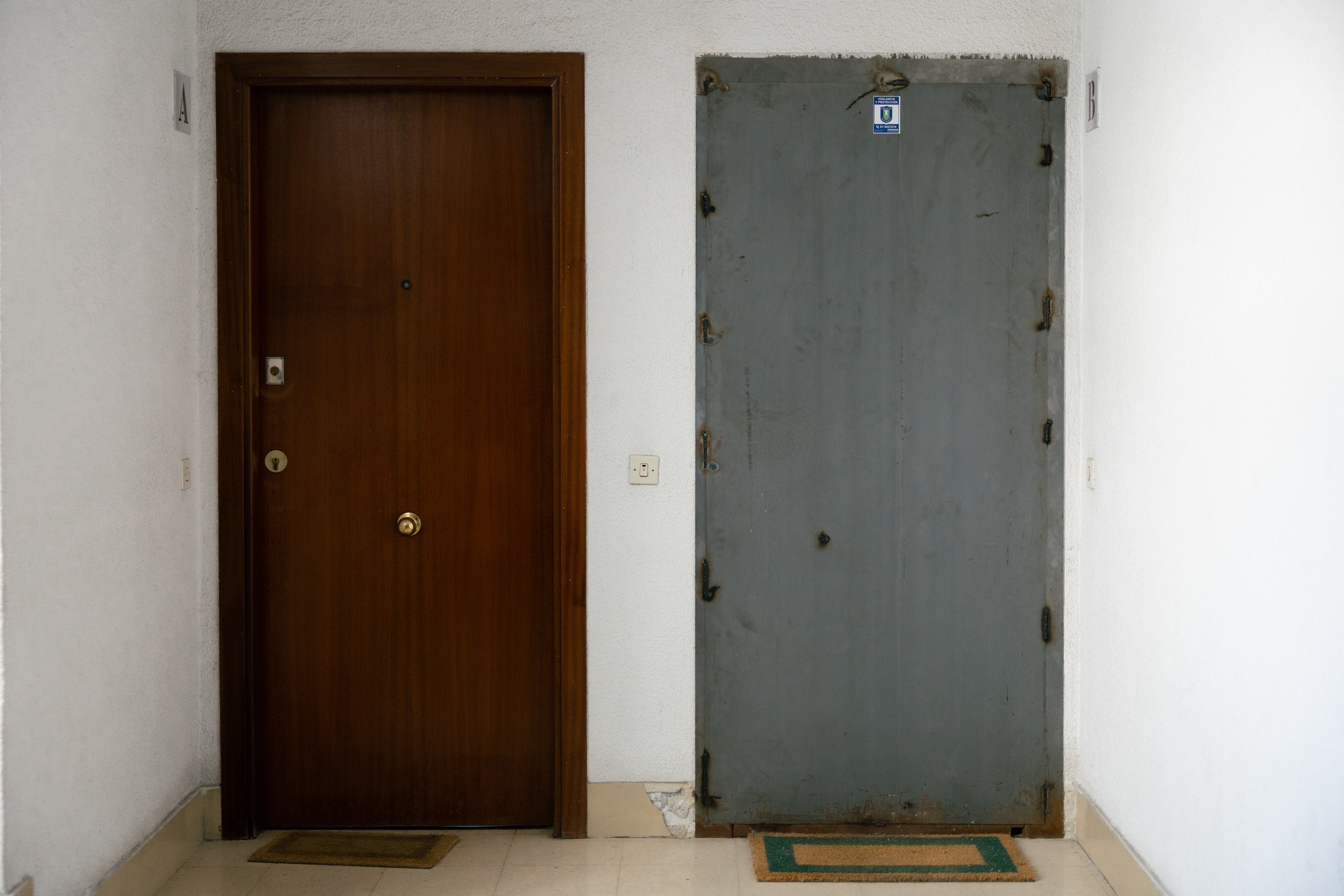 Un piso con puerta acorazada y felpudo a la izquierda, junto a otro liberado, en la calle Camino Alto de San Isidro de Madrid.