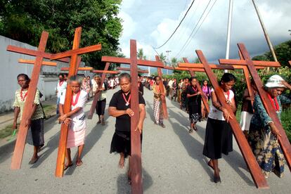 Varias mujeres cargan con cruces de madera mientras rezan en la iglesia de Komoro en Dili, Timor Oriental, durante el Domingo de Ramos domingo.