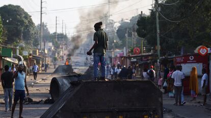 Un joven de pie sobre una barricada levantada este viernes, 25 de octubre, en Maputo durante las protestas contra la elección de Daniel Chapo como presidente de Mozambique.