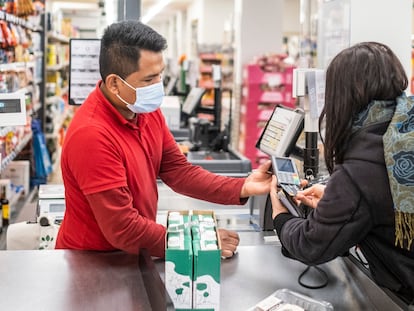 Un dependiente de un Dia en Madrid trabajando en la caja registradora del supermercado.