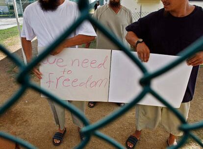 Detenidos chinos uigur, que han sido liberados pero no tienen país a dónde ir, muestran pancartas a periodistas que han visitado el centro de detención Camp Iguana en Guantánamo