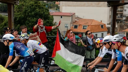 Los ciclista del equipo Israel Premier Tech pasan ante las protestas propalestina durante la etapa de la Vuelta Ciclista a España este martes entre Poio y Mos-Castro de Herville (Pontevedra).