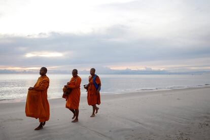 Monjes budistas caminan por la playa pidiendo limosnas como ofrenda, en Hua Hin (Tailandia). 