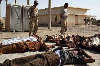 Dos soldados de la Guardia Nacional iraquí observan los cadáveres de varios de los reclutas muertos a manos de la insurgencia.