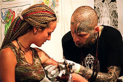 Un profesional tatuando a una chica en la 6º Convención Internacional de Tatuajes.
