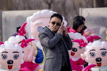 Un hombre llama por teléfono delante de muñecos de Pleasant Goats, una serie animada de televisión china