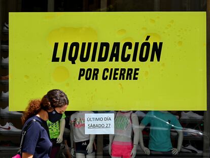 Una mujer camina delante de un comercio a punto de cerrar en Madrid.