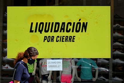 Una mujer camina delante de un comercio a punto de cerrar en Madrid.