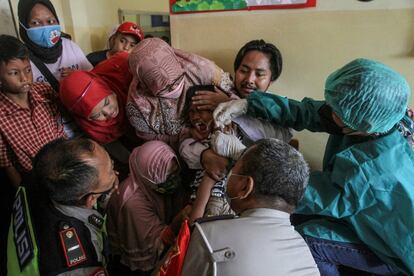 Varias personas sujetan a un niño que va a recibir la vacuna contra el coronavirus, en Indonesia. El país sigue con un programa de vacunación masiva para niños de 6 a 11 años.