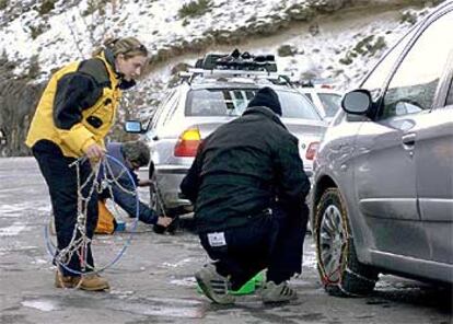 Dos conductores colocan cadenas a sus automóviles cerca de Benasque.