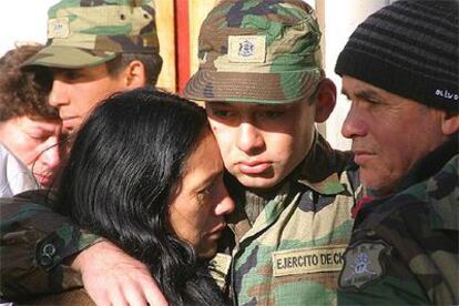 Dos reclutas rescatados anoche tras una tormenta de nieve en los Andes abrazan a sus familiares.