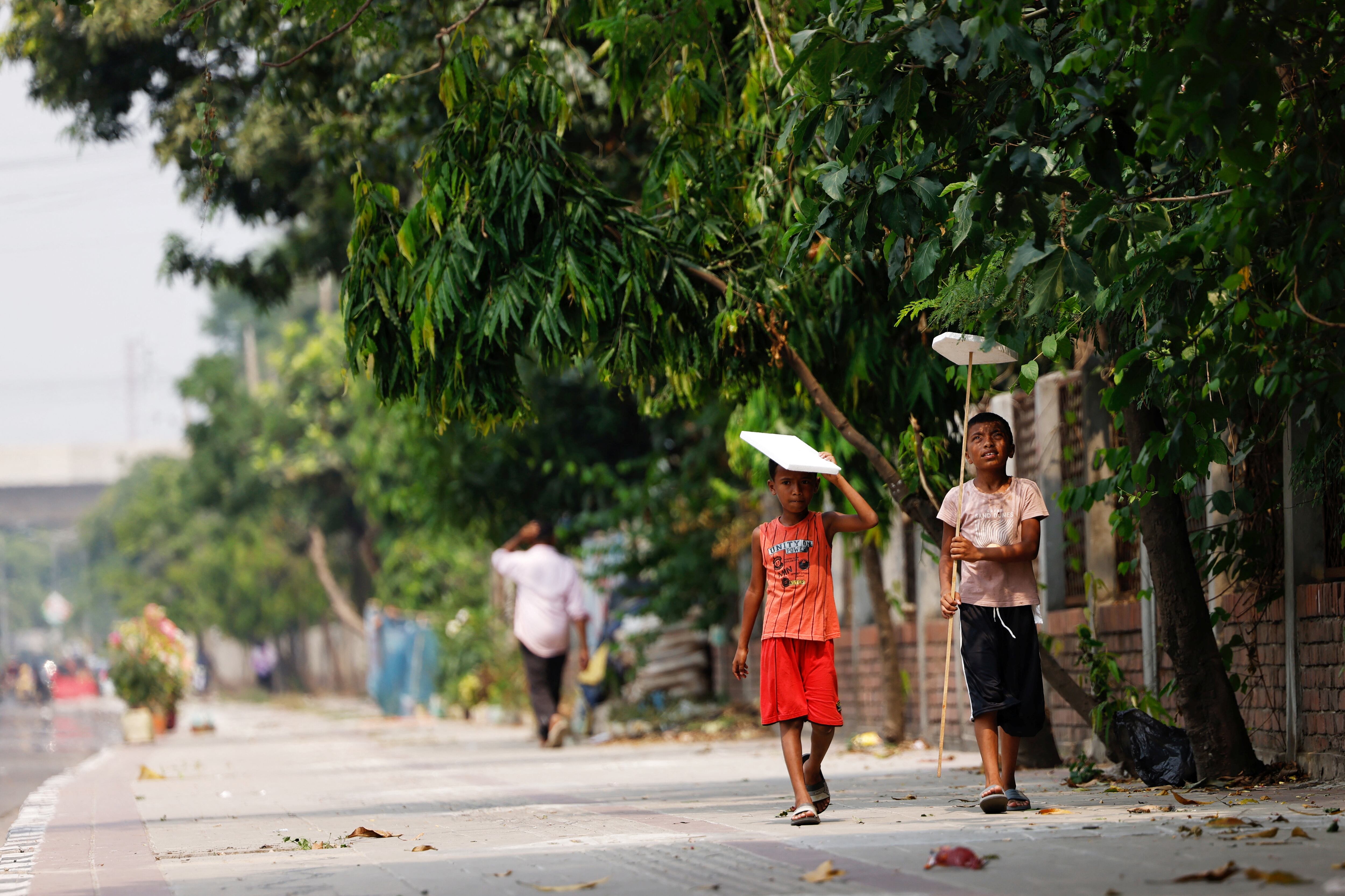 Dos niños se protegían del sol con trozos de poliespán en Daca (Bangladés), el domingo.