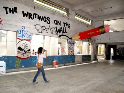 Un lápiz gigante escribe en la pared.