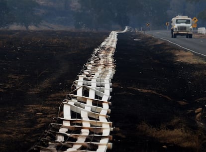 A burnt fence lies on its side as firefighters continue to battle the "Valley Fire" in the town of Middletown, California on September 15, 2015. Wildfires sweeping across California are threatening the US state's famed Sequoia trees, with firefighters scrambling to protect the national treasures. AFP PHOTO / MARK RALSTON