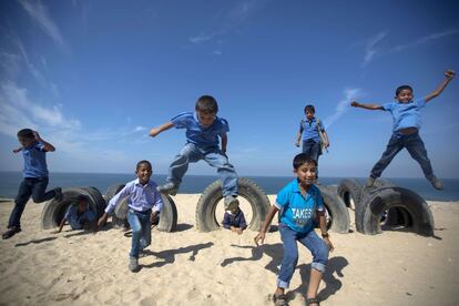 Escolares palestinos juegan con neumáticos en la playa de Gaza, 24 de octubre de 2013.