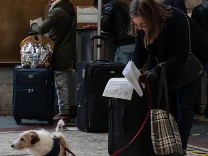 Una mujer con un perro, firmando una declaración de su motivo para viajar en la estación de tren Milano Centrale, el día 10.