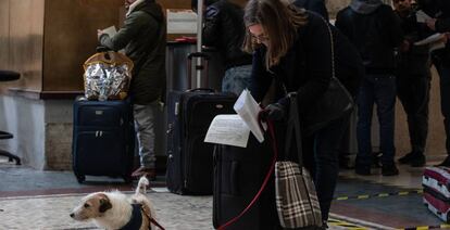 Una mujer con un perro, firmando una declaración de su motivo para viajar en la estación de tren Milano Centrale, el día 10.