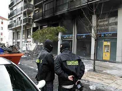 Dos <i>ertzainas</i> vigilan el edificio atacado en Mondragón.