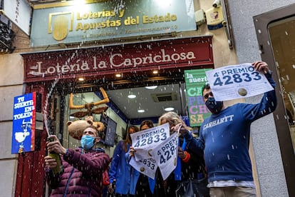 Trabajadores de la administración La Caprichosa de Toledo muestran el cartel de venta del número 42833, que ha sido agraciado con uno de los cuartos premios.