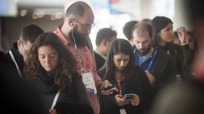 Varias personas utilizan sus teléfonos móviles.