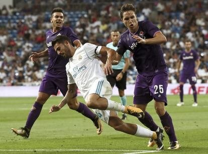 El centrocampista del Real Madrid Dani Ceballos (c) cae entre el argentino Giovanni Simeone (i) y Federico Chiesa (d), de la Fiorentina.