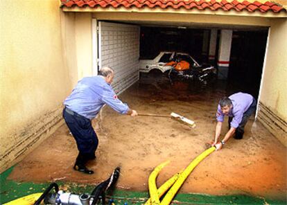 Dos bomberos extraían ayer con una bomba de achique el agua de un aparcamiento inundado en Segur de Calafell.