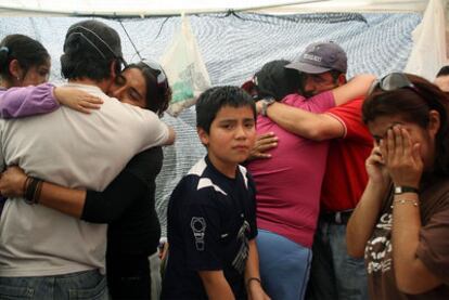 Familiares de los 33 mineros sepultados se abrazan el domingo tras conocer que siguen con vida.