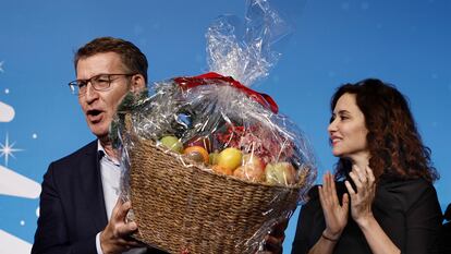 El presidente del PP, Alberto Núñez Feijóo, sostiene una cesta de fruta junto a la presidenta de la Comunidad de Madrid, Isabel Díaz Ayuso, durante la cena de Navidad del PP de Madrid, celebrada este lunes.