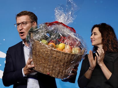 El presidente del PP, Alberto Núñez Feijóo, sostiene una cesta de fruta junto a la presidenta de la Comunidad de Madrid, Isabel Díaz Ayuso, durante la cena de Navidad del PP de Madrid, celebrada este lunes.