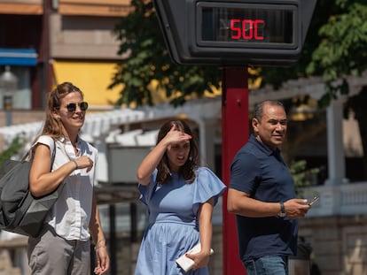 Varias personas pasan ante un termómetro al sol que marca 50 grados, ayer martes en Ourense, que supera las previsiones y llega a los 43,5 grados.