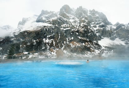 Piscina exterior del balneario Walliser Alpentherme Burgerbad & Spa Leukerbad, en Suiza, con la montaña Gemmi como telon de fondo.