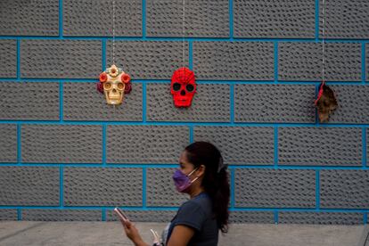 Una mujer toma fotografías frente a las tradicionales mascaras de calavera.