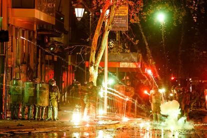 Un grupo de policías recibe el impacto de unos fuegos artificiales lanzados por manifestantes en el centro de Santiago.