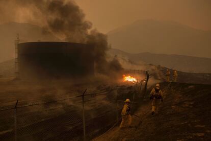 Los bomberos trabajan junto a un tanque de agua devorado por las llamas en Santa Clarita, el 23 de julio de 2016.