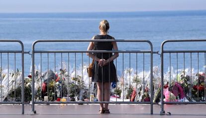 Una mujer contempla las flores depositadas en el Paseo de los Ingleses.