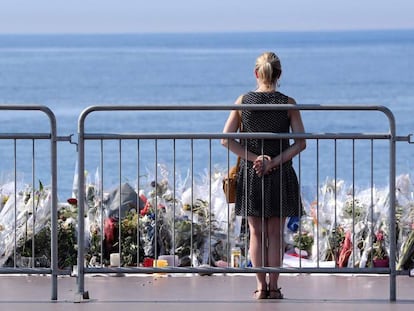 Una mujer contempla las flores depositadas en el Paseo de los Ingleses.