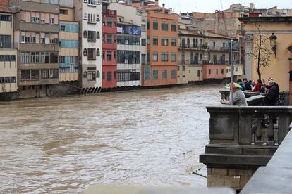 Veïns de Girona contemplen l'Onyar, que baixa amb força per sota dels ponts de la ciutat.