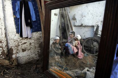 Tres niños reflejados sobre un espejo en su casa derrumbada en Peshawar (Pakistán).