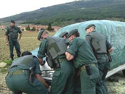 Guardias civiles cubren la furgoneta desde la que ayer fue lanzada una granada contra un cuartel, al fondo.